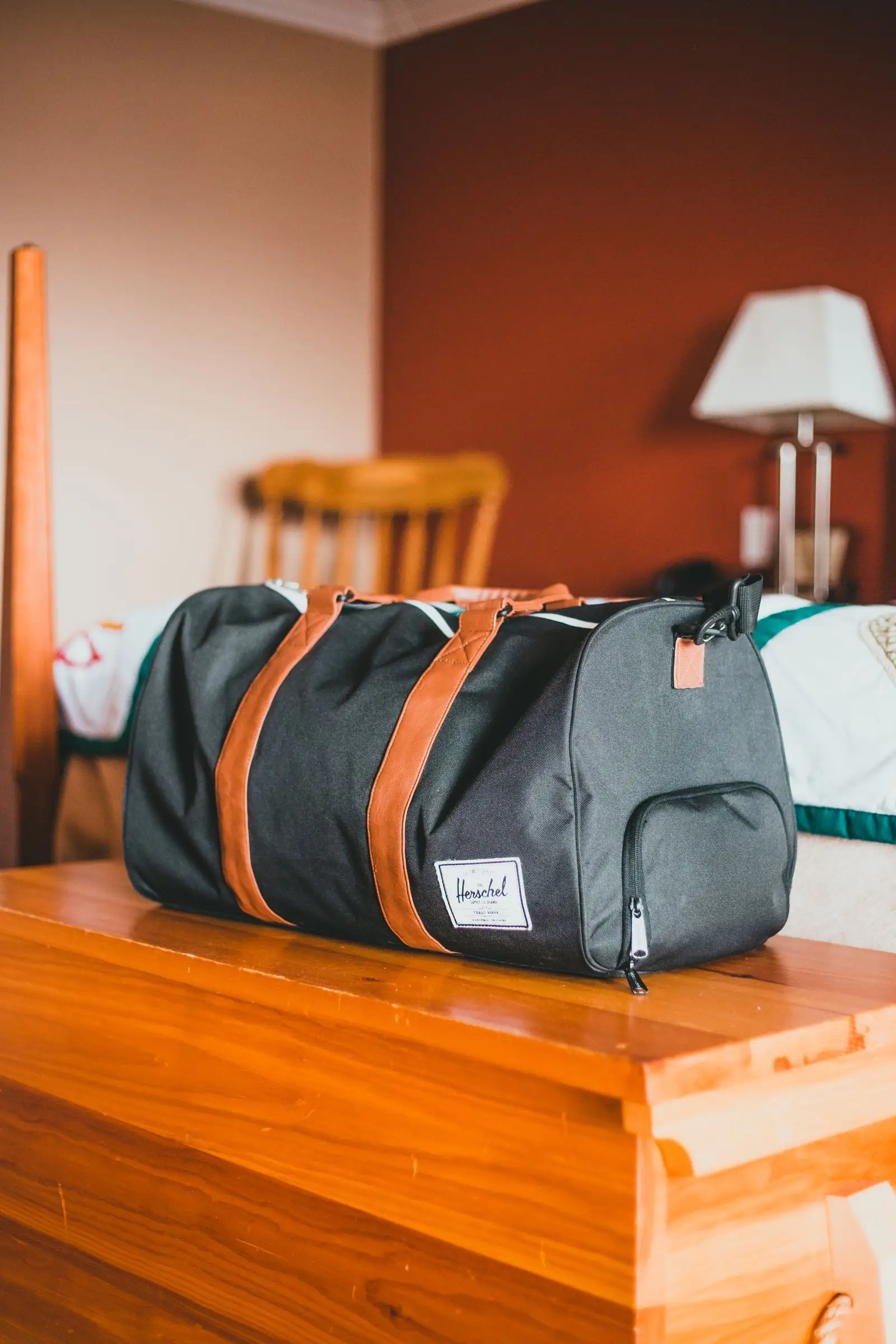 Navy duffel bag with leather handles resting on a wooden table