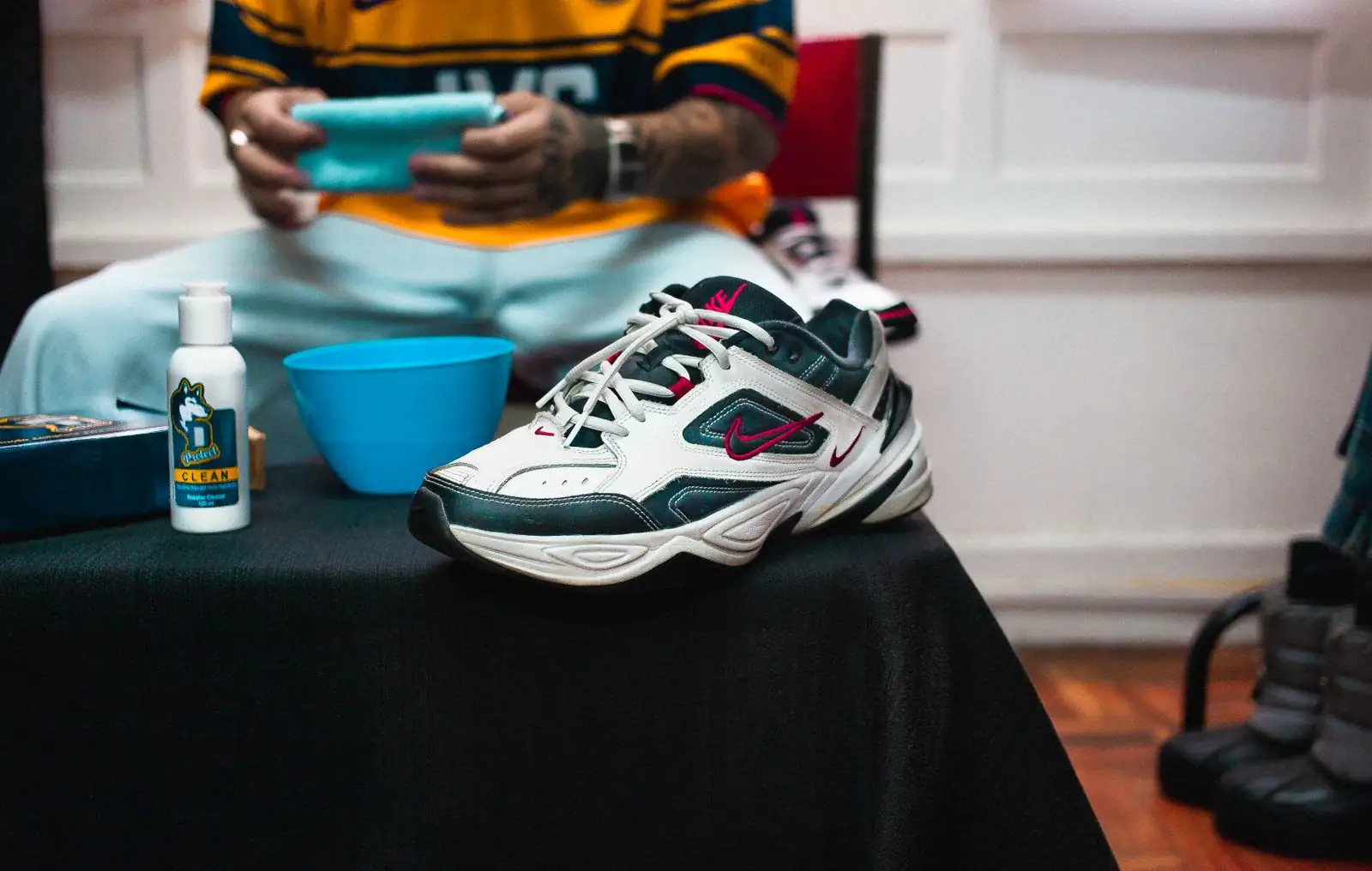 Sneakers beside a cleaning bottle and brush ready for shoe cleaning